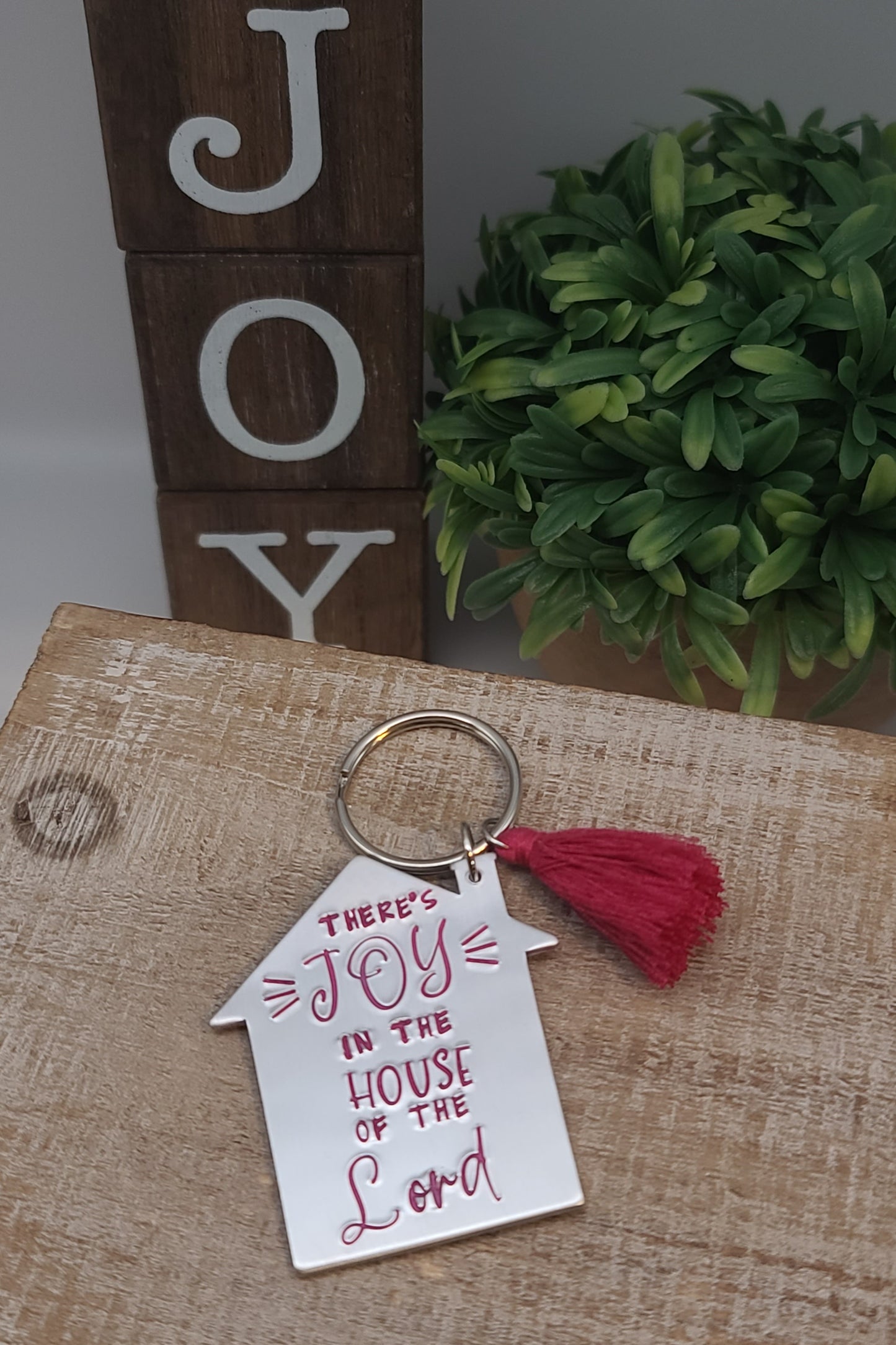 Shape of a house, hand stamped "Joy in the House of the Lord", coordinating tassel: aluminum keychain.